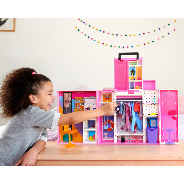 Fille joue avec grand dressing Barbie transportable