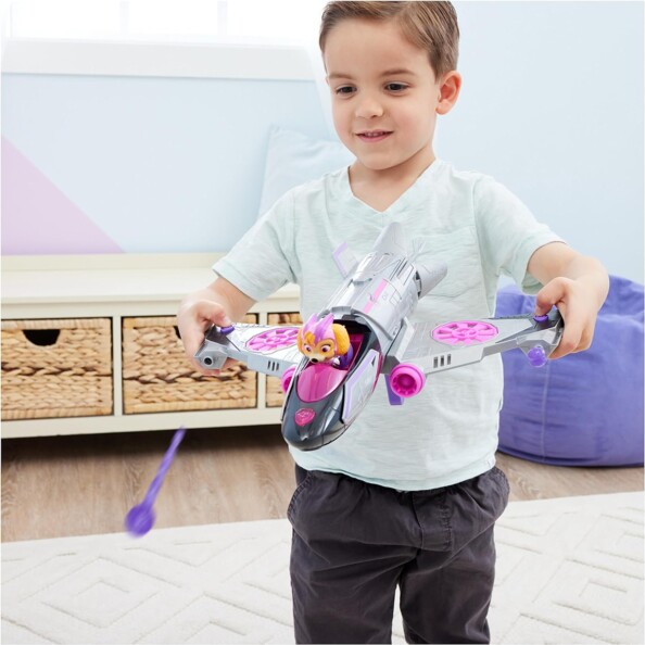 Petit garçon tenant entre les mains l'avion de sauvetage de Stella lançant deux projectiles violets par pression sur les boutons situés sur les extrémités des ailes