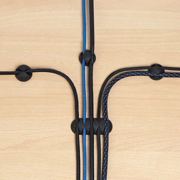 Mise en situation de la fixation de 5 câbles de chargement et de transfert de données à quatre clips organiseurs autocollants différents