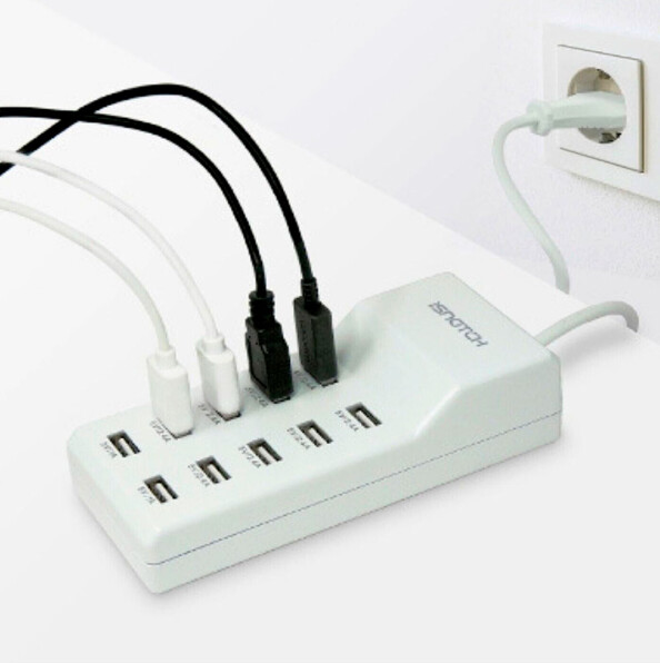 Mise en situation de 4 câbles de chargement et d'alimentation USB noirs et blancs branchés aux ports USB-A du bloc d'alimentation multiprise USB raccordé à une prise de courant secteur