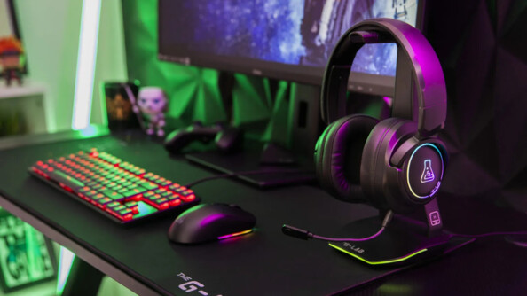 Setup gaming rétroéclairé en LED RVB avec PC, casque audio sur support, clavier filaire, souris sans fil, effets personnels et grand tapis de souris rectangulaire