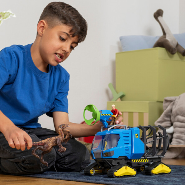 Enfant jouant avec le véhicule chenillé Schleich et le Dakotaraptor