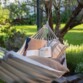 Hamac fixé à deux arbres en pleine nature comme couchage d'appoint avec oreillers et livres posés dedans