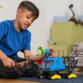 Enfant jouant avec le véhicule chenillé Schleich et le Dakotaraptor